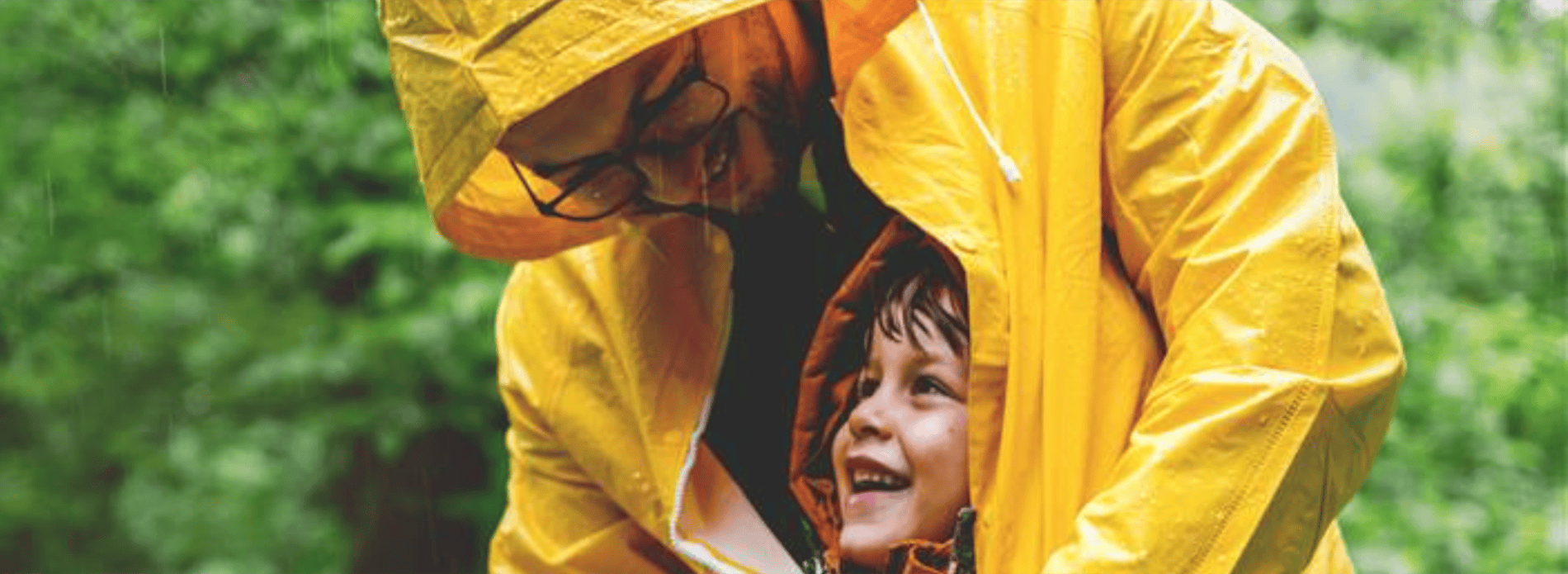 father shielding his young son from the rain with his coat