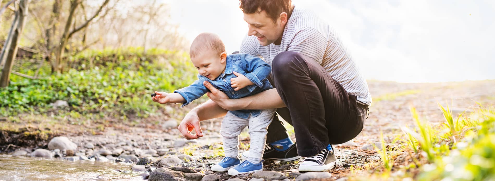 father and toddler son playing in a stream