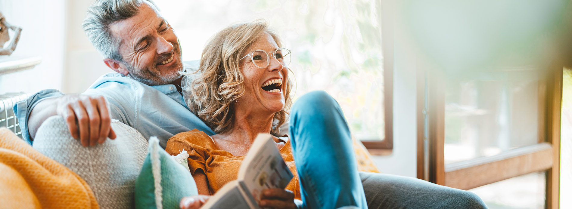 Older couple sitting on sofa together laughing