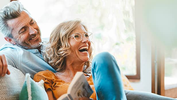 Older couple sitting on sofa together laughing