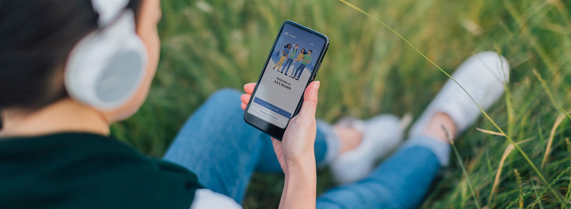 Woman sitting in a a field looking at her phone